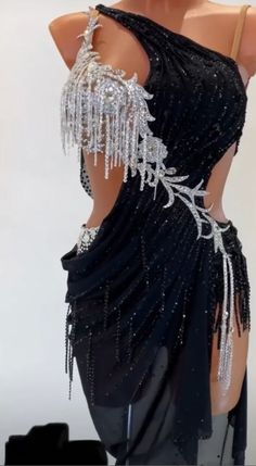 the back of a woman's black dress with silver beads and chains on it