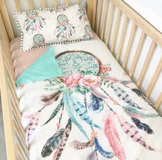 a baby crib with a blanket and pillows on it's side, next to a pillow