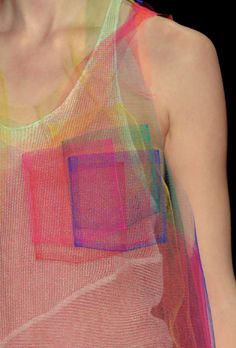 a woman wearing a tank top with colorful squares on it