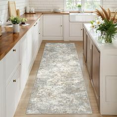 a kitchen with white cabinets and wooden counter tops, along with a rug on the floor