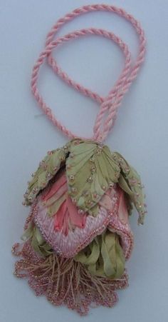 a pink and green bag hanging from a string on a white surface with other items in the background