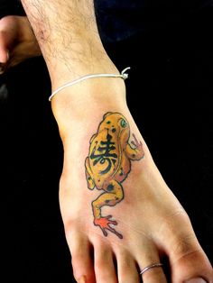 a man's foot with a tattoo on it that has a small yellow frog on it