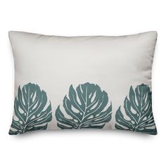 a white and blue pillow with green leaves on the front, sitting on a white background