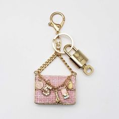 a pink purse keychain hanging from a gold chain