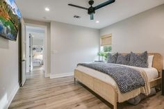 a bedroom with white walls and wood flooring has a large bed in the middle