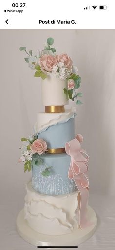 a three tiered cake with flowers and leaves on the top is decorated in pastel blue, pink and white