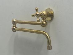 an old fashioned brass faucet on the wall with two handles and nozzles