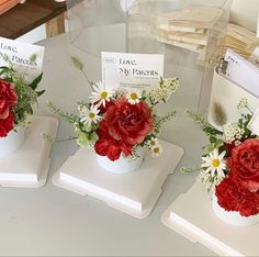 three white vases with red and white flowers in them