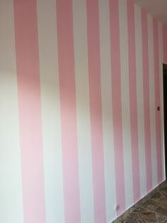 an empty room with pink and white striped walls