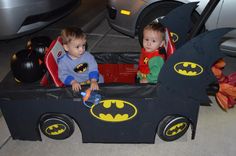 two toddlers sitting in a batman car costume