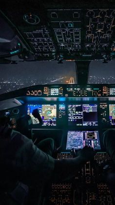 two pilots are in the cockpit of an airplane at night with their screens on and lights on