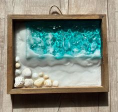 an ocean scene with shells and sand in a wooden frame