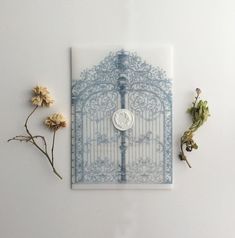 a white and blue gate surrounded by dried flowers on a white surface with a coin in the middle