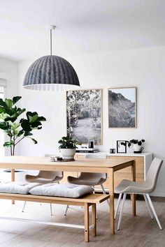 an image of a dining room with white walls and wood furniture in the center, along with pictures on the wall