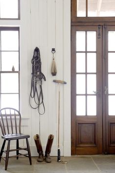 a pair of boots and a hat hang on the wall next to a wooden chair