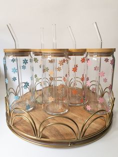 four glasses are sitting on a tray with gold rims and flowered glass lids