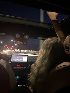 two people in a car driving down the road at night with their hands on the steering wheel