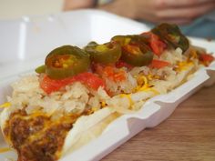 a hot dog with toppings and rice in a styrofoam container