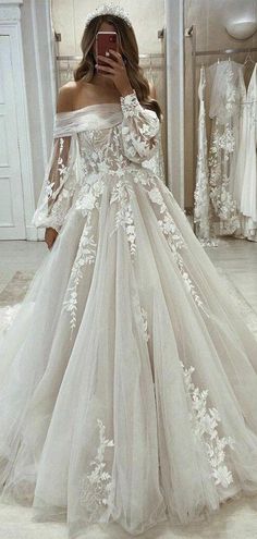 a woman taking a selfie in a wedding dress with white flowers on the skirt