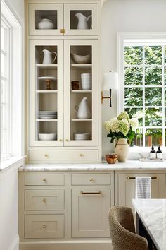 an image of a kitchen with white cabinets and flowers in the vase on the counter