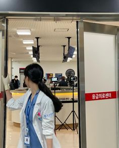 a woman in a lab coat is entering a building with her hand out to the side