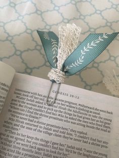 an open book with a blue and white ribbon attached to it