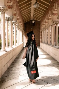 a woman in a graduation gown is standing on the walkway with her hands in her pockets