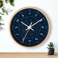 a clock with zodiac signs on it next to a potted plant