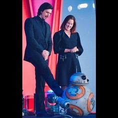 two people standing next to each other in front of a star wars droid robot