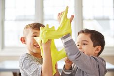 two young boys are playing with green gloves