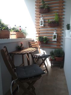 a balcony with potted plants on the wall and wooden table in front of it