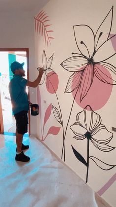 a man painting a wall with flowers on it