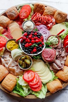 a platter filled with meats, cheeses and vegetables next to crackers