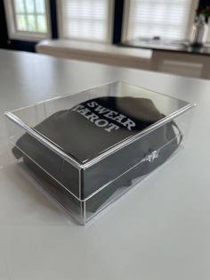 a clear plastic box sitting on top of a white table with windows in the background