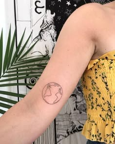 a woman's arm with a small earth tattoo on the left side of her arm