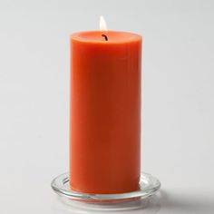 an orange candle sitting on top of a glass holder