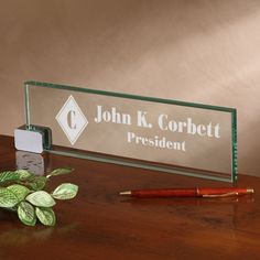 a desk with a pen, plant and glass plaque that says patrick k fielding anesthesiollogist north hospital