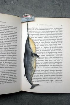 an open book with a fish hanging from it's side