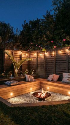 a fire pit surrounded by lights in the middle of a backyard area with wooden fence