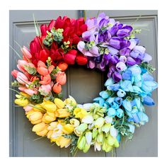 a colorful wreath is hanging on the door with tulips and other flowers around it