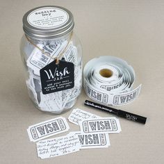 a jar filled with lots of stickers next to a roll of paper and a pen