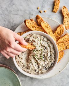 a person dipping some bread sticks into a bowl of cream cheese dip with chives