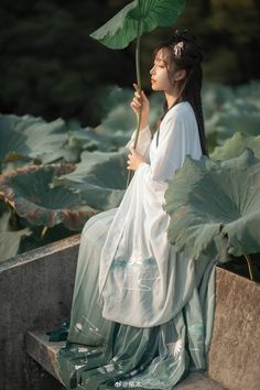 a woman sitting on a bench holding a flower