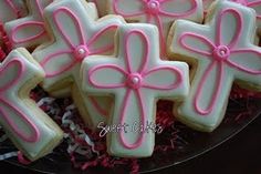 decorated cookies in the shape of crosses on a platter with pink ribbons and bows