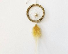 a dream catcher hanging on the wall with a bead and feather decoration attached to it