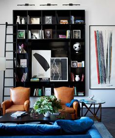 a living room filled with furniture and bookshelves next to a wall mounted book shelf