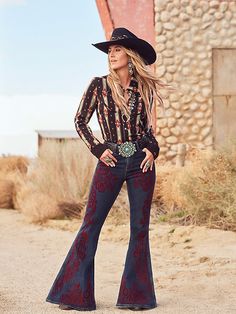 TRIED, TRUE, AND A LITTLE UNTAMED One-of-a-kind Western style. Undeniable star appeal. Turn to the Wrangler® x Lainey Wilson Vintage Flocked Bell Bottoms to make a show-stopping statement on stage and off. The Vintage Flocked Bell Bottom not only honors Lainey’s go-to silhouette but also adds a modern twist thanks to the feminine, velvet maroon flocking embellishment on the front of each leg. This flattering detail doesn’t just lengthen the leg, it makes them look a mile long. Best of all, each Lainey Wilson Style, Lainey Wilson Outfits, Western Chic Fashion, Jean Shirt Dress, Justin Boots Womens, Lainey Wilson, Jennifer Beals, Twisted X Boots, Southwestern Print