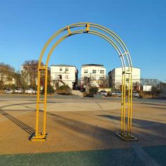 an empty parking lot with yellow arches and buildings in the backgrouds behind it