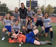 a soccer team posing for a photo on the field with their coach and goalie