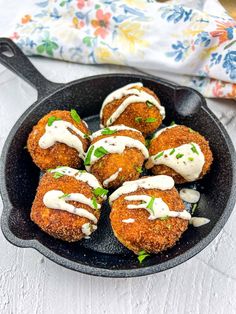 some fried food is in a black skillet on a white tablecloth with flowers